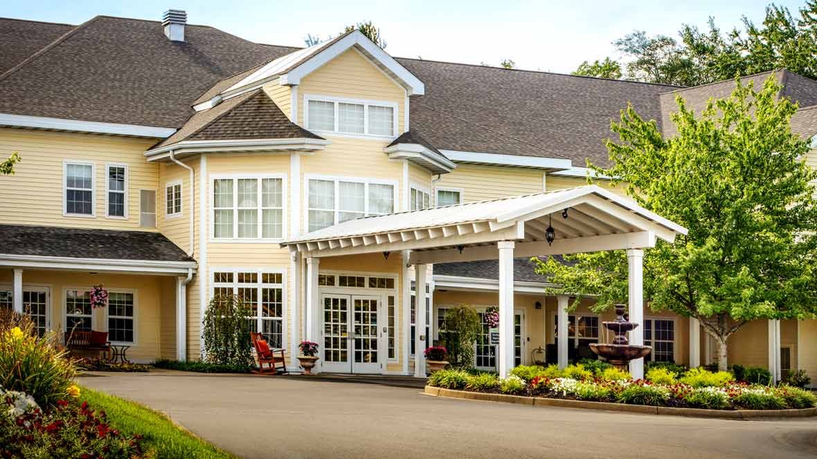 A large residential building with a covered entrance and landscaped garden.