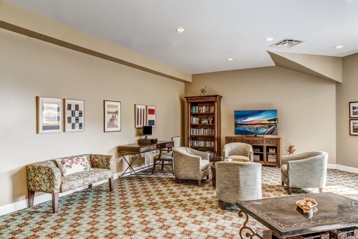 A cozy lounge area featuring comfortable chairs, a bookshelf, and artwork on the walls.