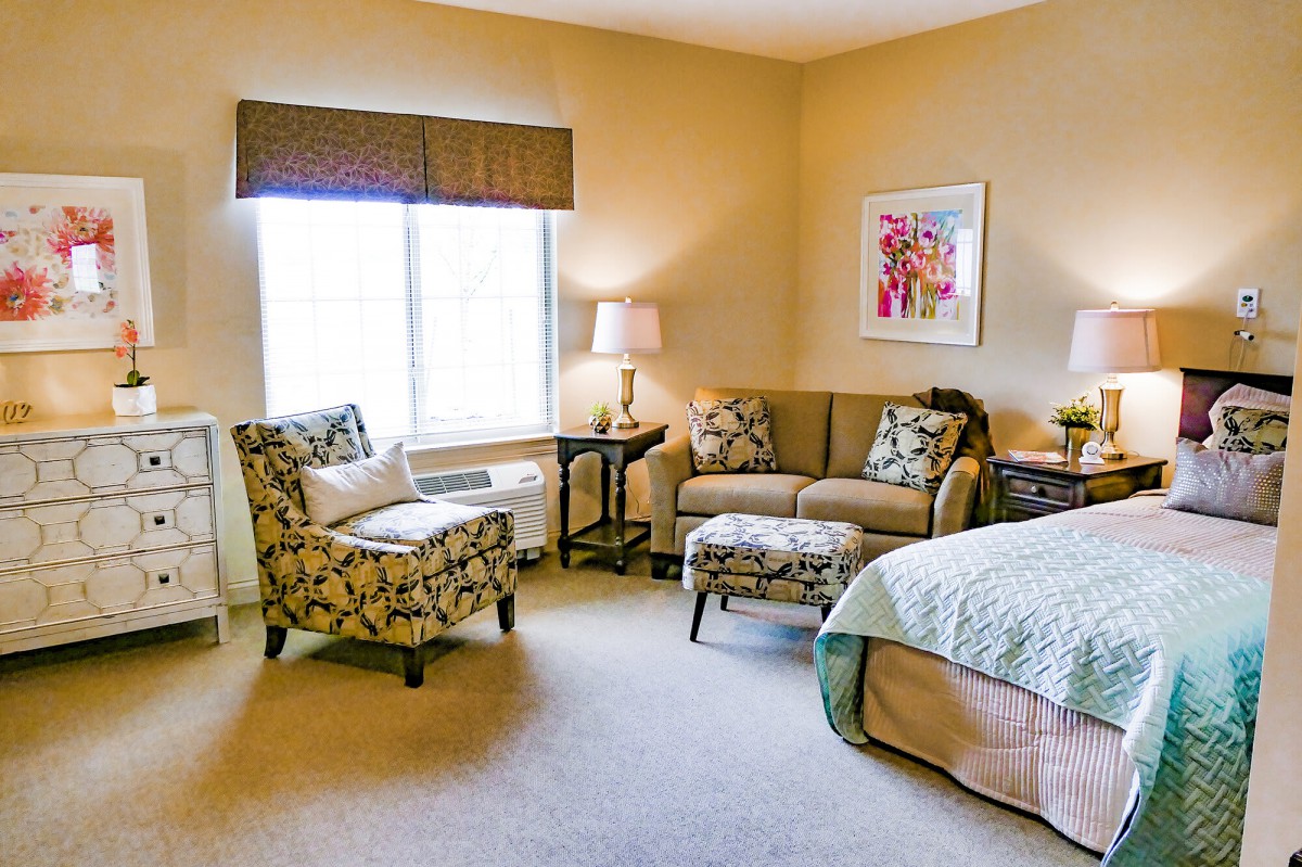 A cozy bedroom featuring a sofa, armchair, and bed with complementary decor.