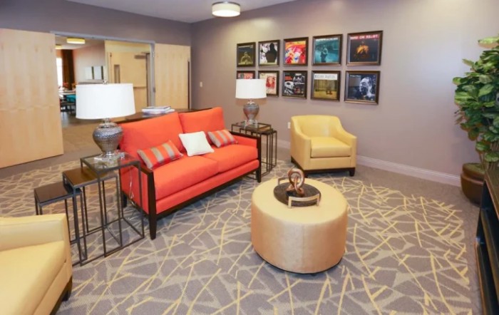 A stylish living room featuring a vibrant orange sofa, a yellow armchair, and modern decor.