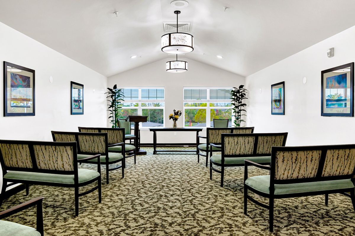 A serene chapel interior with a podium, elegant seating, and large windows.