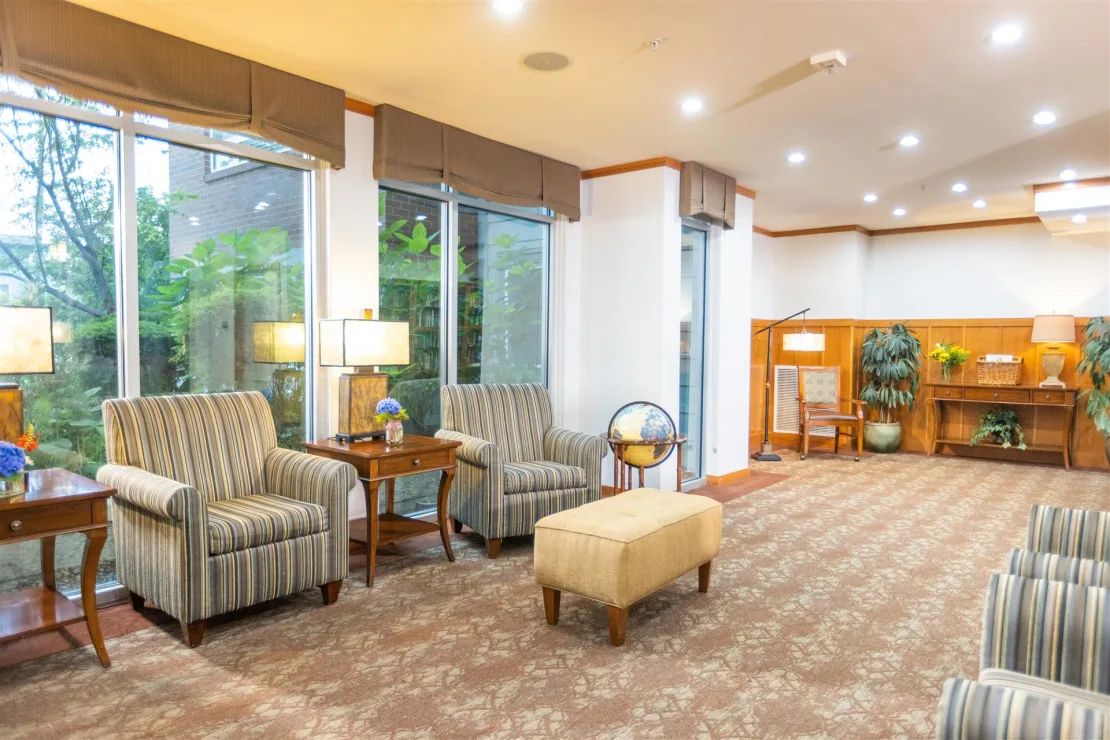A cozy lobby with comfortable seating, large windows, and warm lighting.