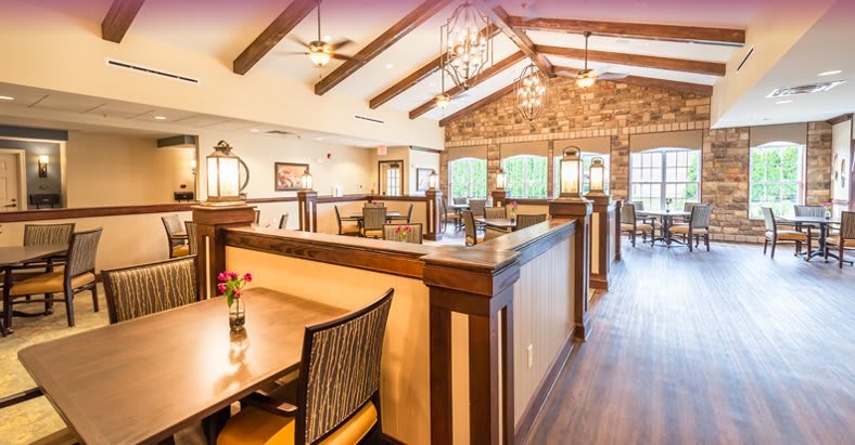 A warmly lit restaurant interior featuring wooden beams, chandeliers, and comfortable seating arrangements.