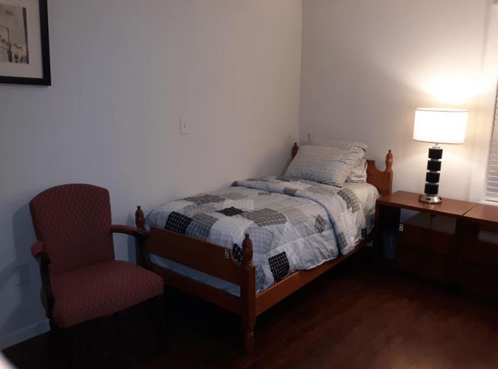 A minimalist bedroom with a single bed, nightstand, and lamp.