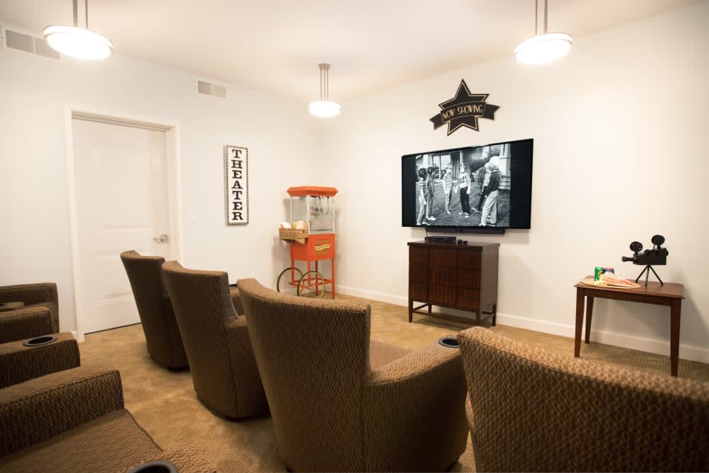 A cozy home theater setup with comfortable seating, a vintage movie playing on the TV, and a popcorn machine in the corner.