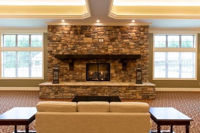 A cozy living room with a stone fireplace and comfortable seating.