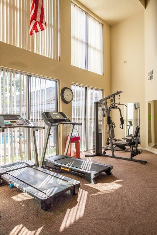 A well-lit gym with treadmills and strength training equipment.