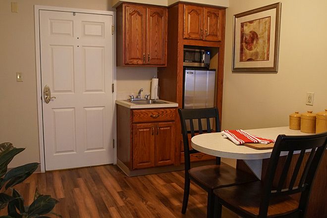 A cozy kitchenette with wooden cabinets, a round dining table, and hardwood flooring.