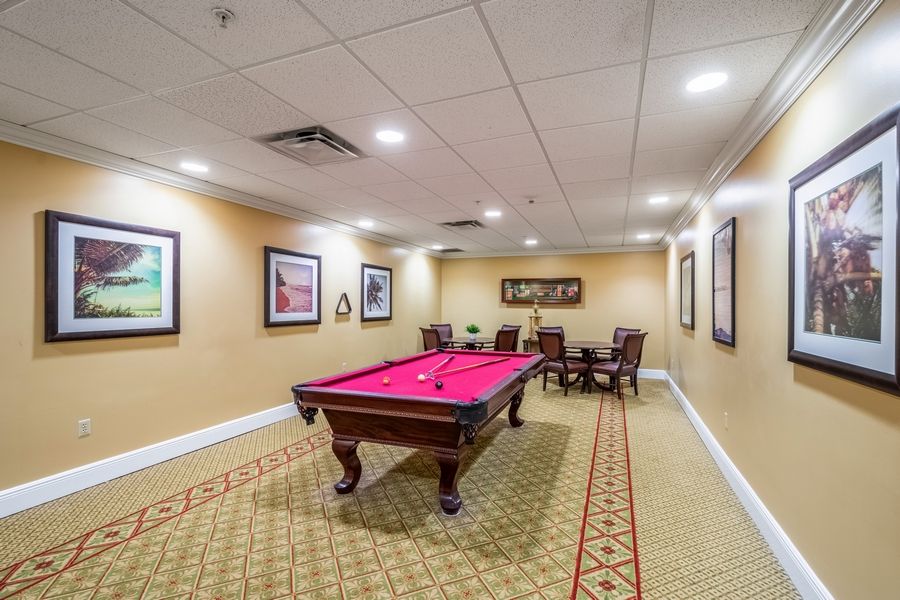 A cozy billiard room featuring a red pool table surrounded by comfortable seating and artwork on the walls.