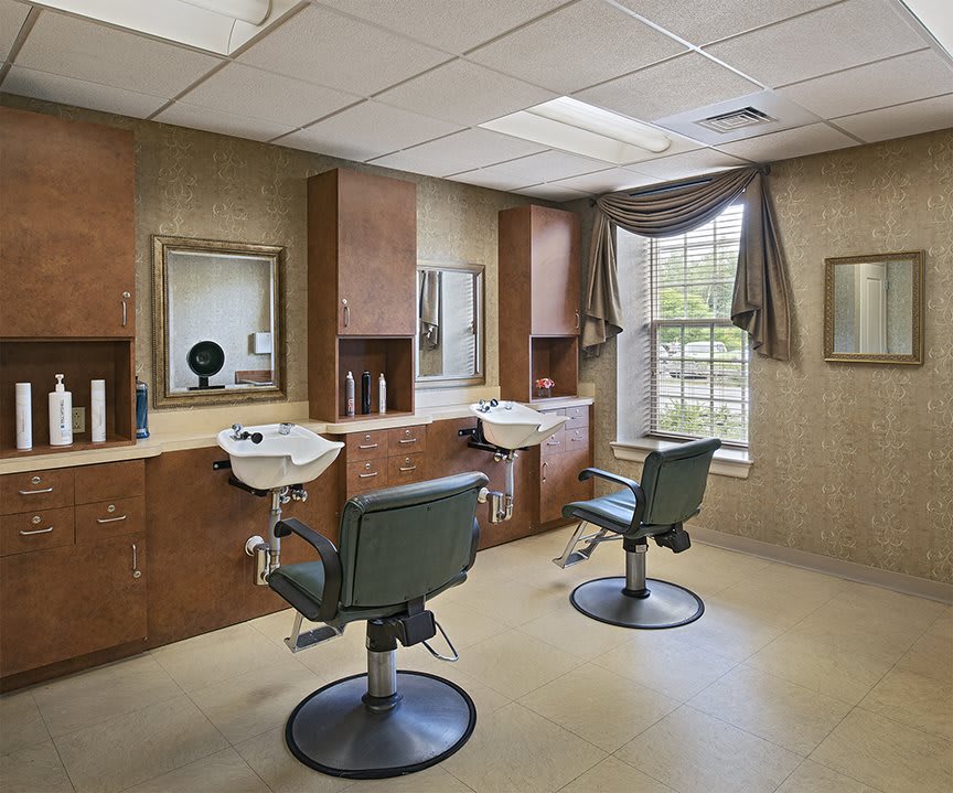 A cozy hair salon with chairs, mirrors, and large windows.