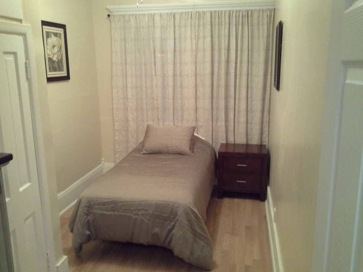 A small, minimalist bedroom with a single bed and nightstand.