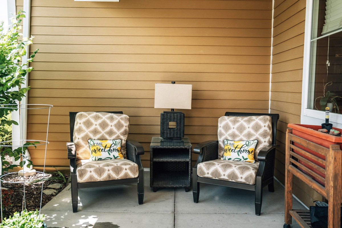 Cozy outdoor seating area with patterned cushions, a side table, and a lamp.