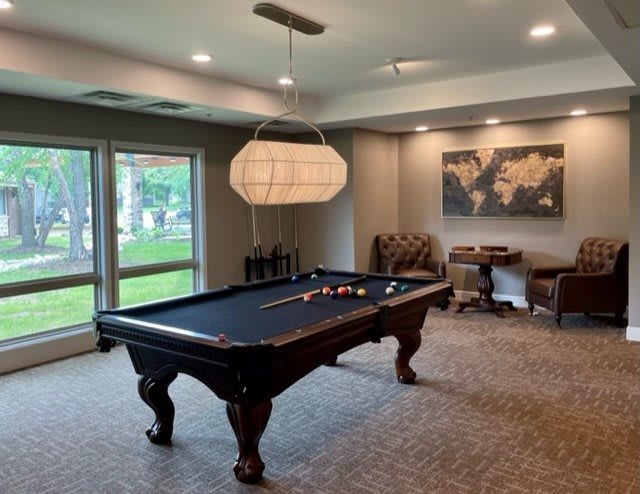 A modern billiard room featuring a pool table, comfortable seating, and elegant lighting.