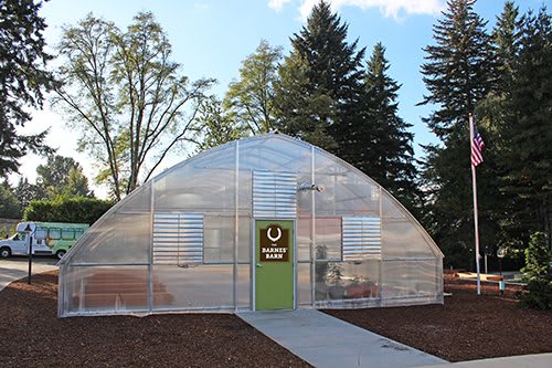 A modern greenhouse surrounded by trees.