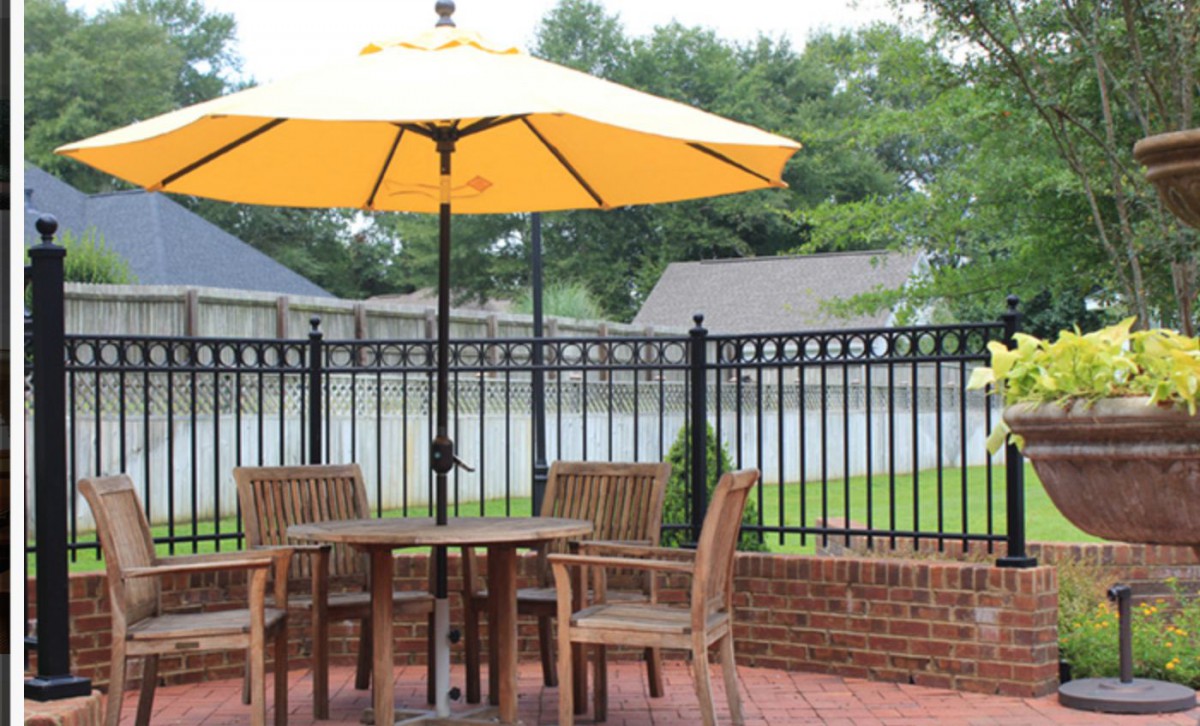 A cozy backyard patio with wooden furniture and a large yellow umbrella.