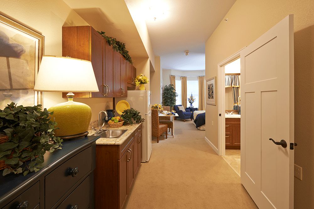 A cozy hallway leading to a living area, featuring warm lighting and wooden cabinetry.