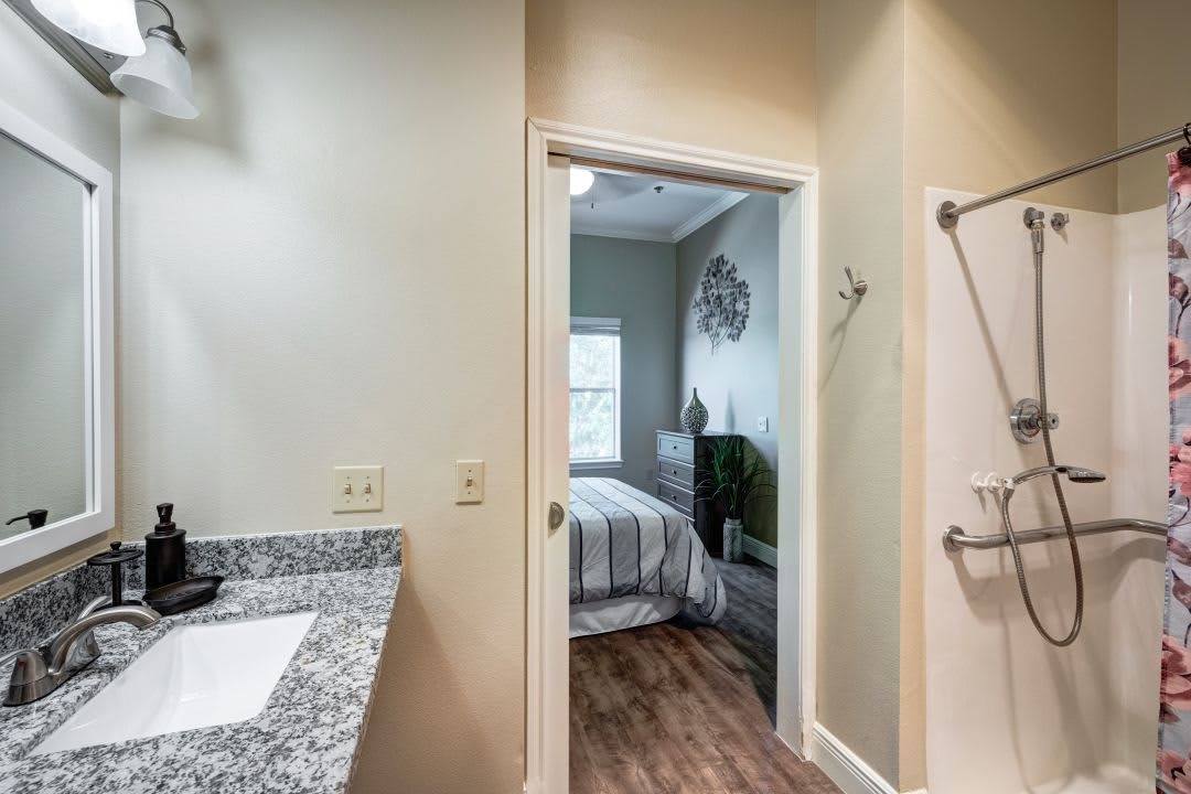 View of a bedroom through a bathroom doorway, featuring modern decor and wooden flooring.