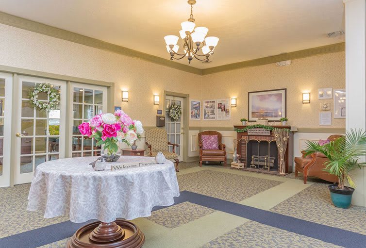 A cozy lobby area with a chandelier, fireplace, and floral decorations.