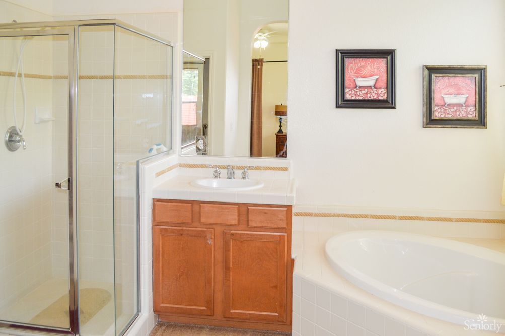 A modern bathroom with a glass shower, bathtub, and sink with wooden cabinet.