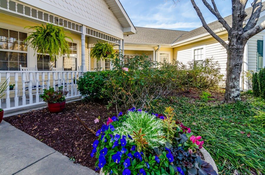 A charming house with a well-maintained garden and blooming flowers around the front porch.