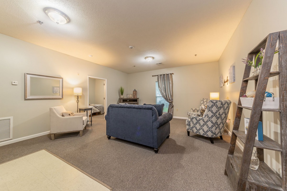 A cozy living room with a blue sofa, patterned armchair, and soft lighting.