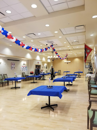 A spacious event hall prepared with blue tables and festive decorations, ready for a celebration.