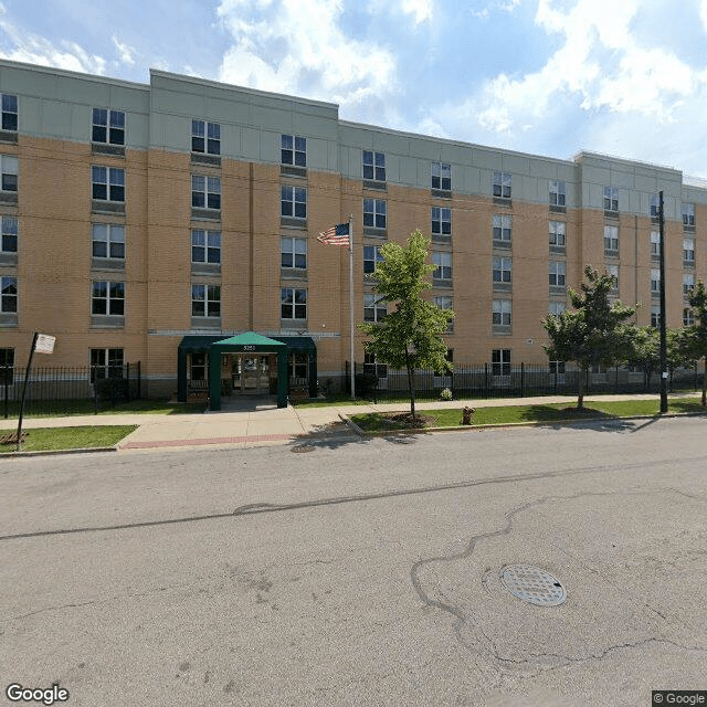 A multi-story residential apartment building with trees lining the street on a clear day.
