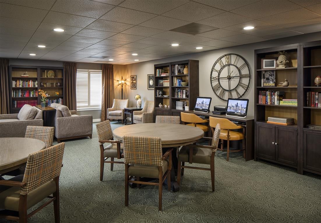 A cozy reading room with bookshelves, a seating area, and computers available for use.