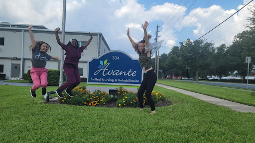 Two individuals joyfully jumping in front of the Avante sign.