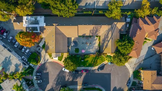 Aerial view of a residential house with a driveway and surrounding greenery.