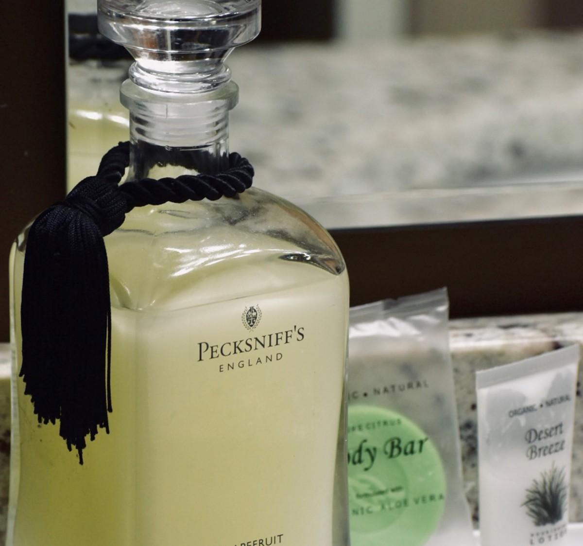 A luxury bottle of fragrance displayed next to a mirror with other toiletries.
