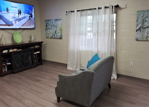 A cozy living room setup featuring a gray sofa, television, and light curtains.