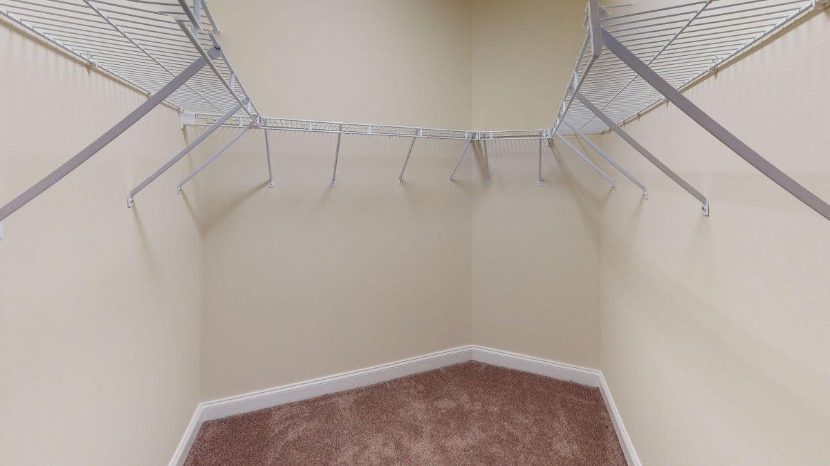 An empty closet with wire shelving and carpeted flooring.