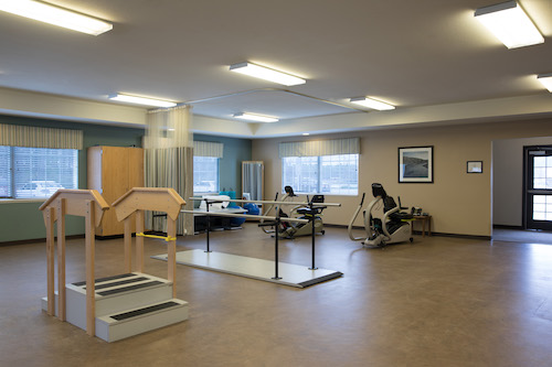 A spacious physical therapy room equipped with various exercises and rehabilitation tools.