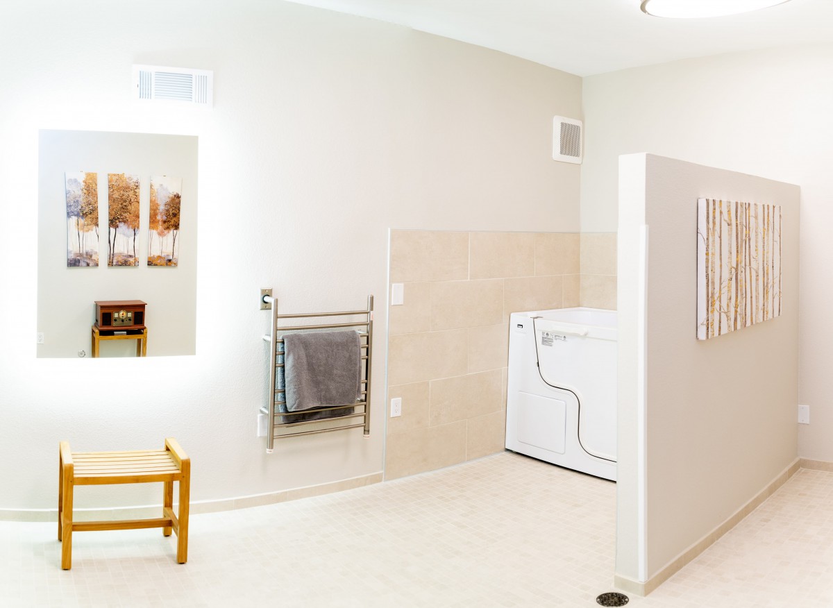 A spacious bathroom with a washer and dryer, featuring a mirror and towel rack.