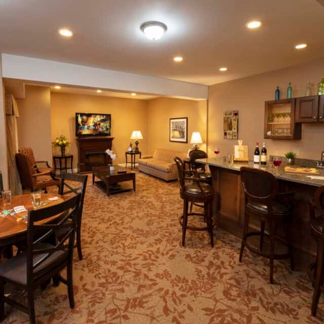 A cozy basement with a home bar, seating area, and television.
