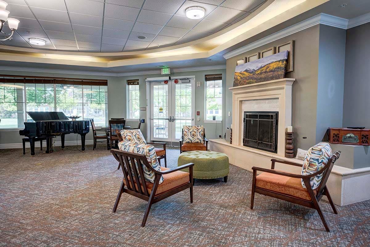 A cozy living room with a seating area, fireplace, and a piano.
