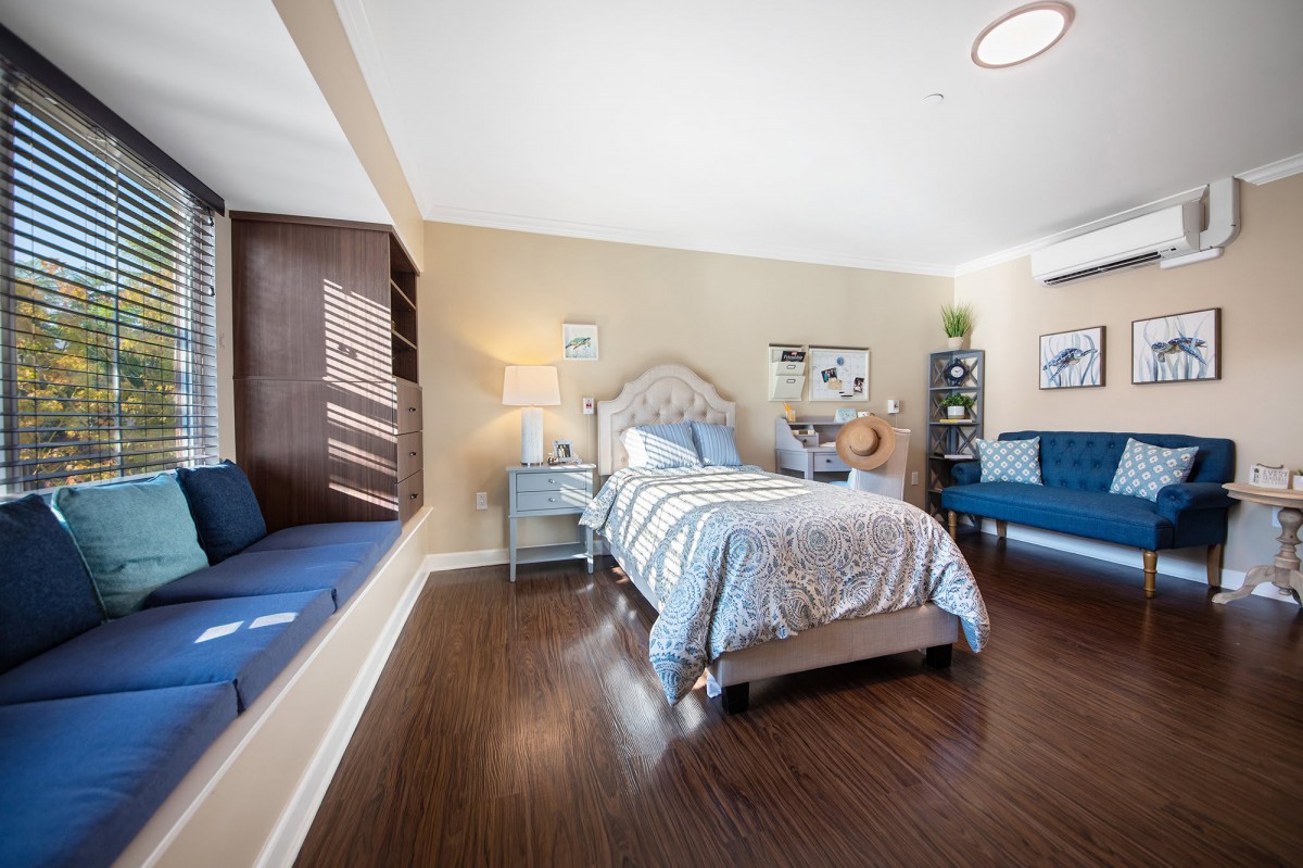 Spacious bedroom with a cozy bed, window seat, and elegant decor.