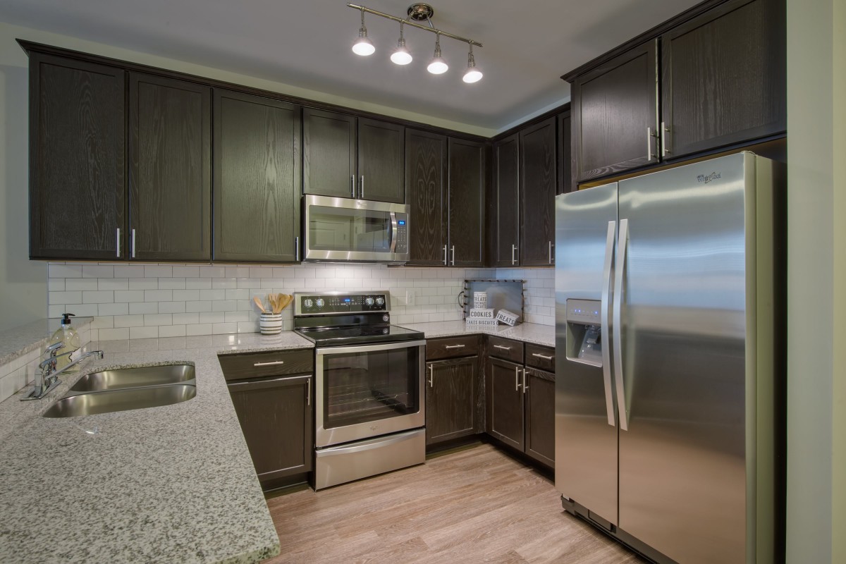 A modern kitchen featuring stainless steel appliances and dark cabinetry.