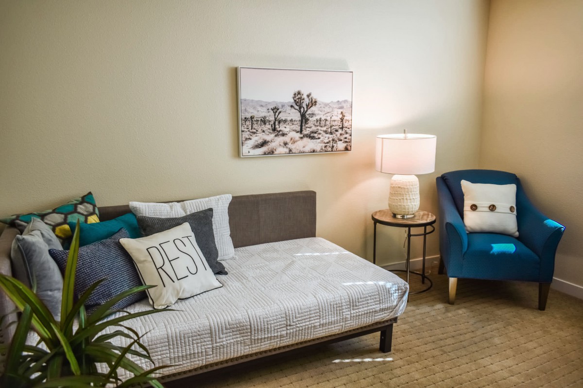 A cozy bedroom interior with a bed, lamp, and chair.