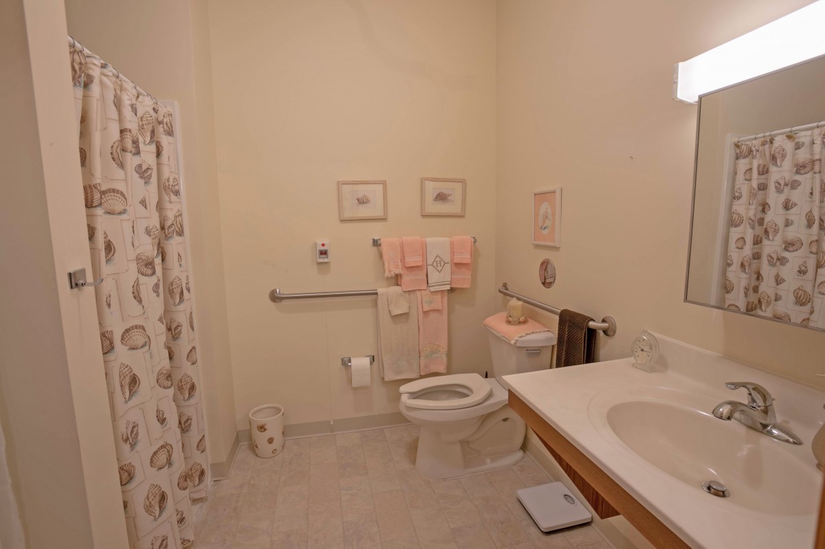 A clean and organized bathroom with a shower, toilet, sink, and neatly arranged towels.