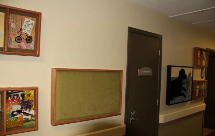 A hallway featuring a notice board mounted on beige walls, with a closed door nearby.