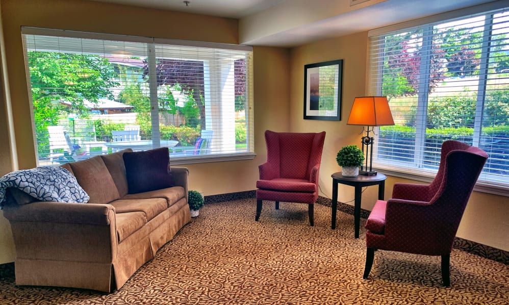 A cozy living room with a sofa, armchairs, and a warm lamp by the window.