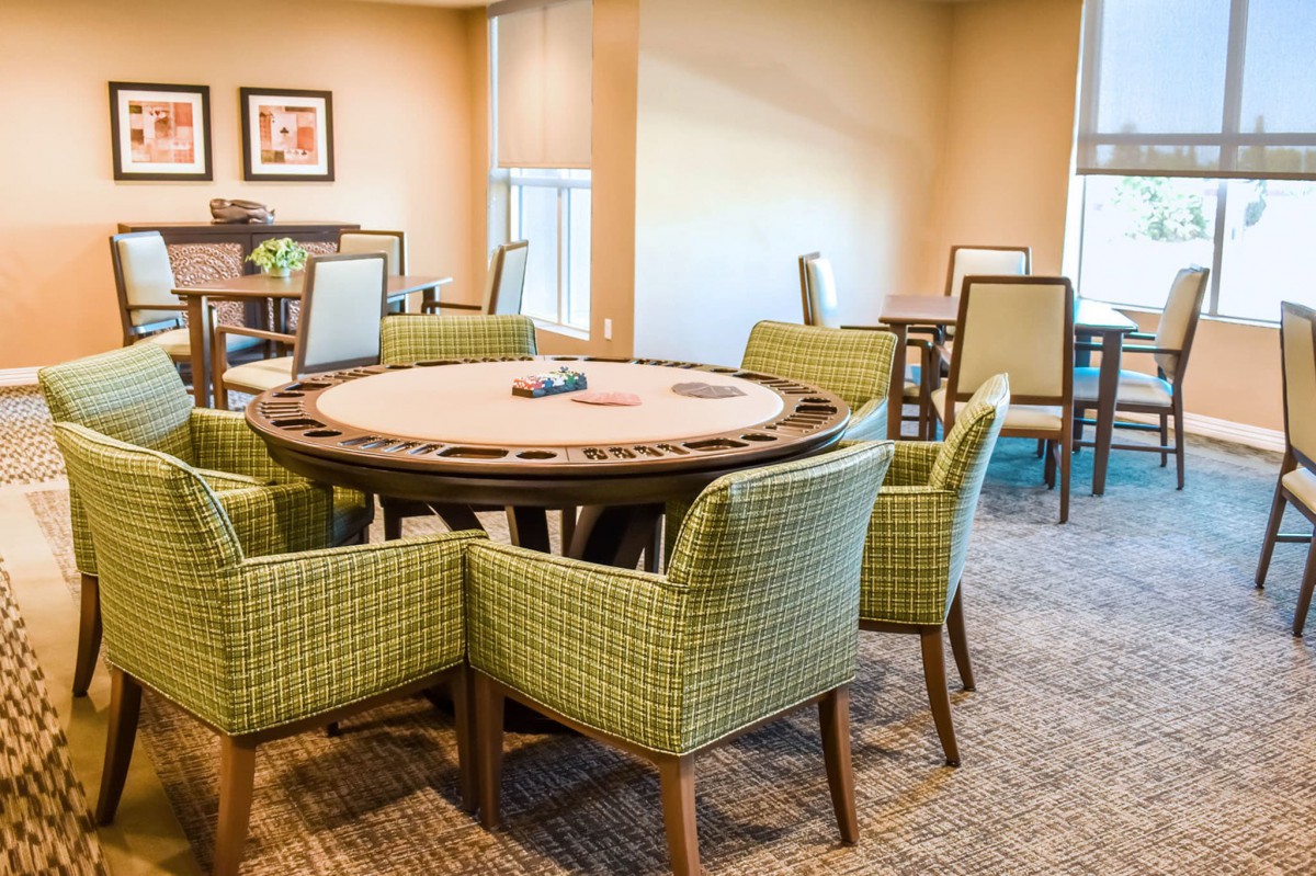 A cozy game room featuring a poker table surrounded by green patterned chairs.