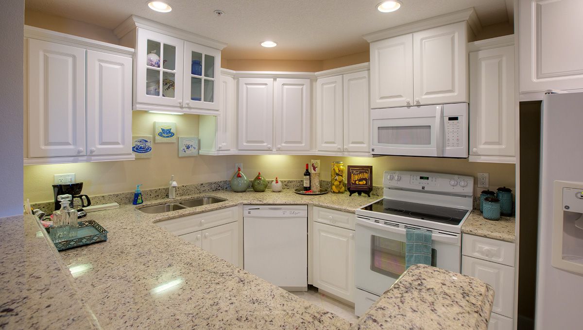 A modern kitchen with white cabinets and granite countertops.