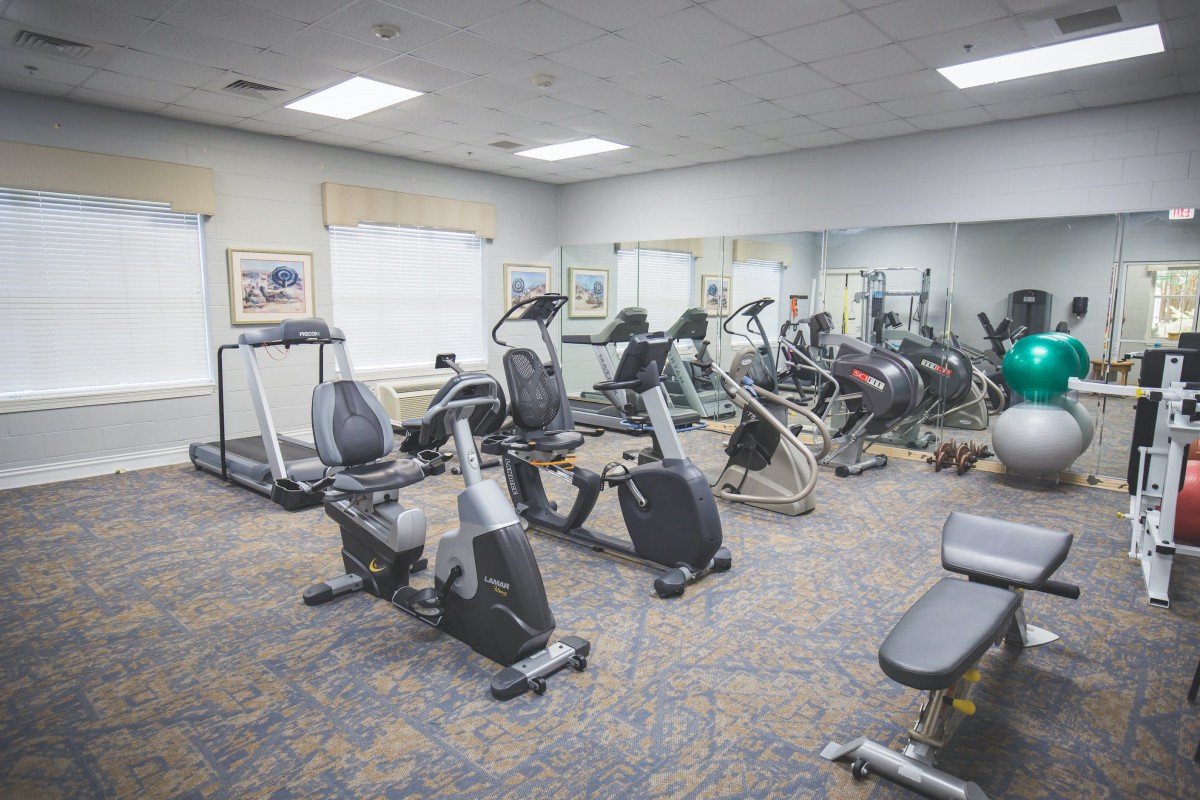 A gym room with various exercise and cardio machines.