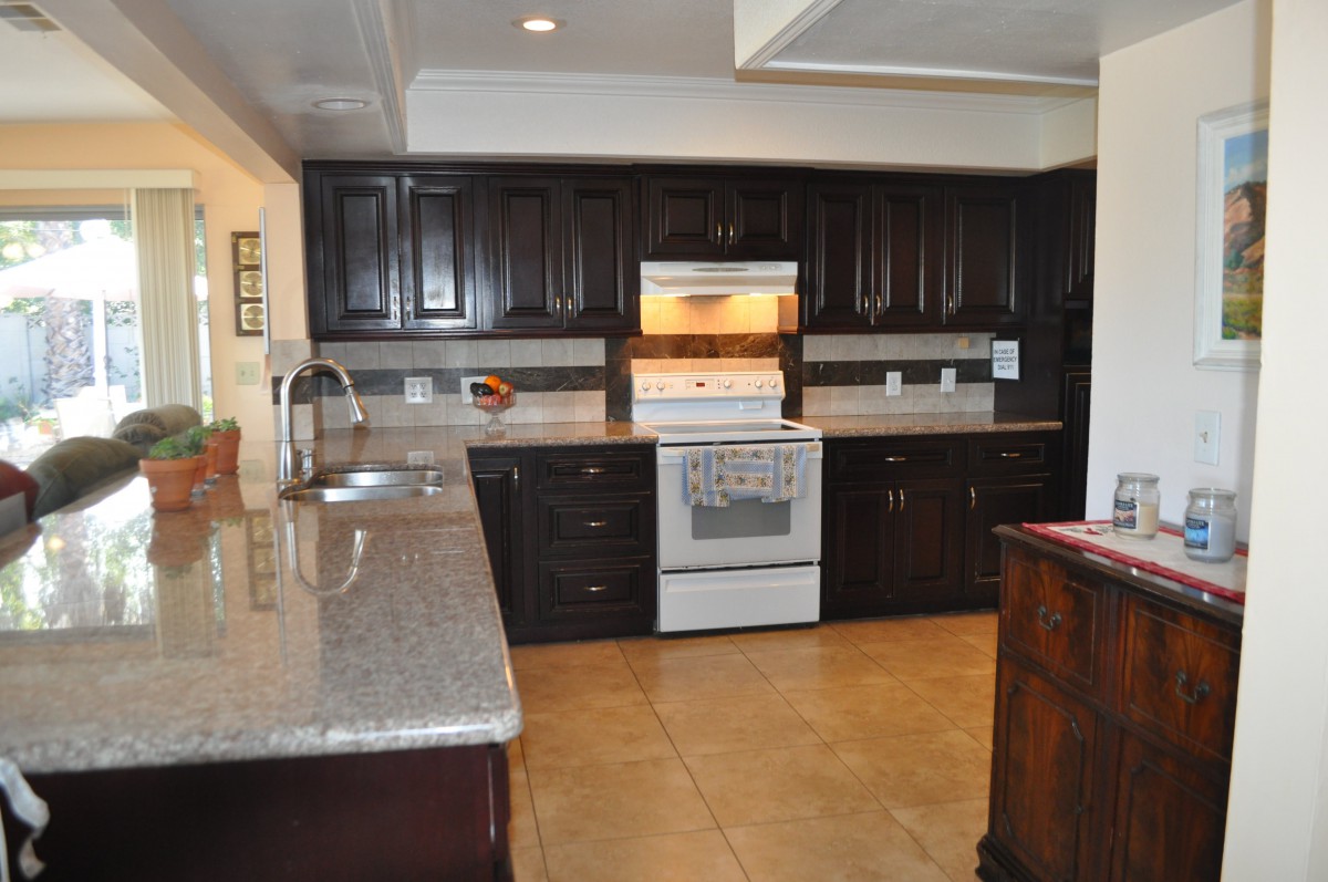 A modern kitchen with dark cabinets and a granite countertop.