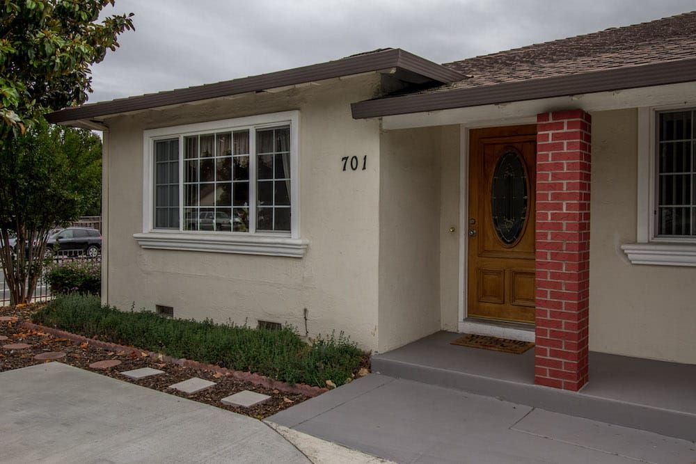 The front entrance of a residential house with a wooden door and brick accents.
