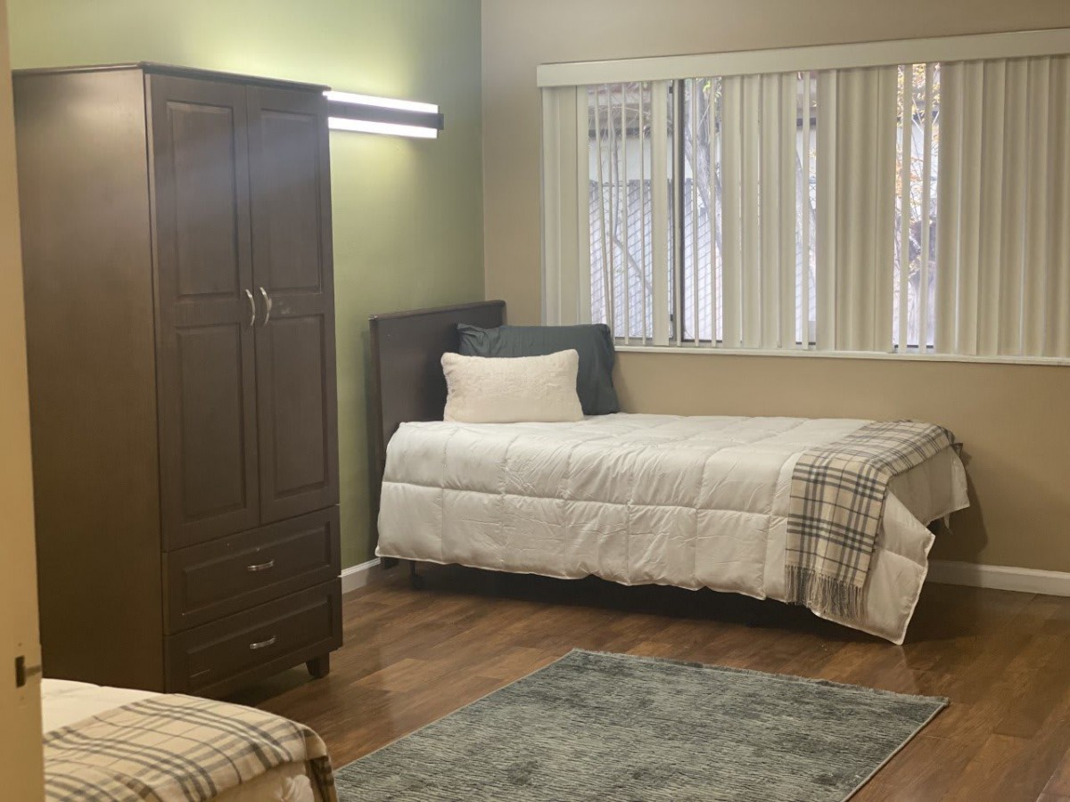 A tidy bedroom with a single bed, wardrobe, and window.