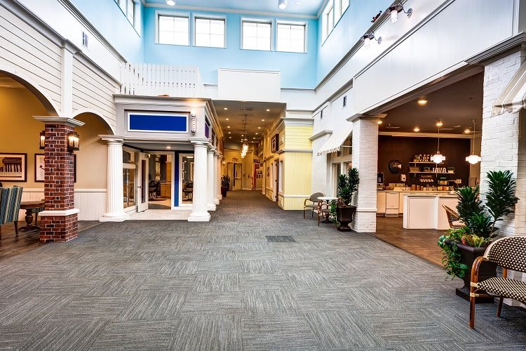 An empty shopping mall interior with storefronts and classical architectural features.